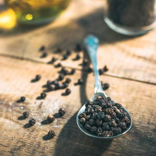 black peppercorns on a teaspoon