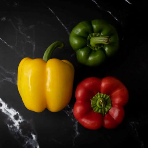 a red, a yellow, and a green pepper on a marbled background